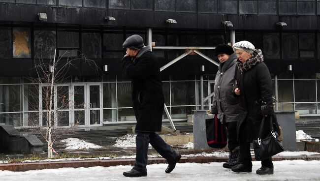Жители Донецка на фоне поврежденного в результате обстрела здания. Архивное фото