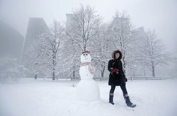 Девушка рядом со снеговиком в парке во время снежной бури в Чикаго