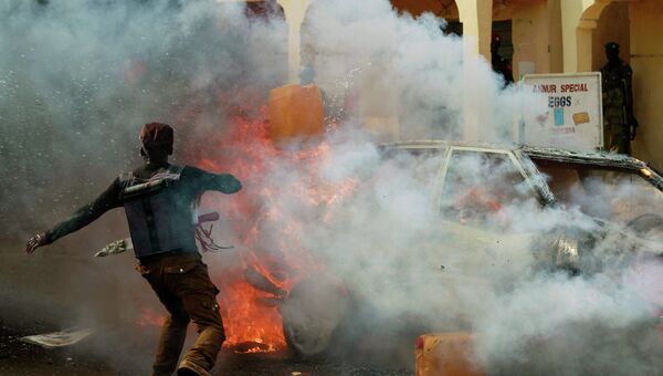 Человек тушит машину, загоревшуюся в результате взрыва на парковке в Нигерии