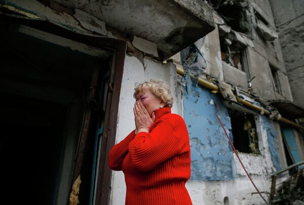Женщина плачет возле разрушенного жилого дома в городе Енакиево