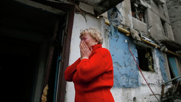 Женщина плачет возле разрушенного жилого дома в городе Енакиево