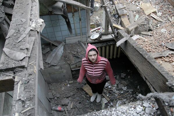 Женщина осматривает разрушенный дом после обстрела Донецка