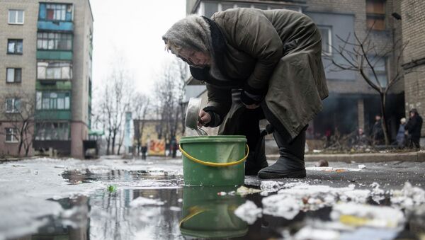 Пожилая женщина собирает воду из лужи в Дебальцево