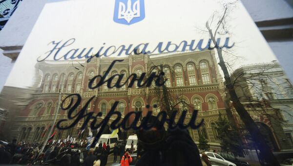 Вывеска Национального банка Украины с отражением активистов кредитного Майдана во время акции. Архивное фото