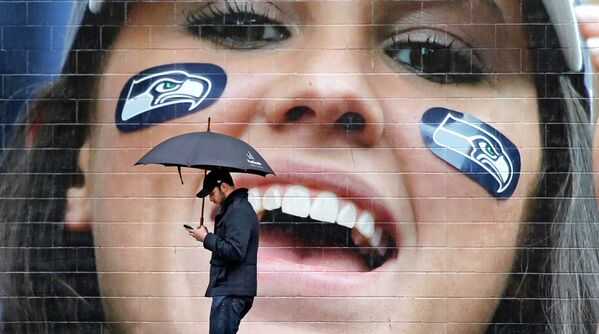 Человек проходит мимо фотографии поклонницы Сиэтл Сихокс в Вашингтоне, США