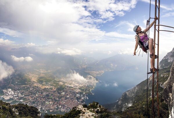 Альпинистка из Великобритании поднимается по лестнице на склоне горы на высоте 1000 метров. Италия, 2015 год