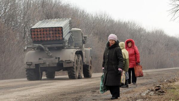 Жители Дебальцево на обочине дороги, по которой следует военная техника