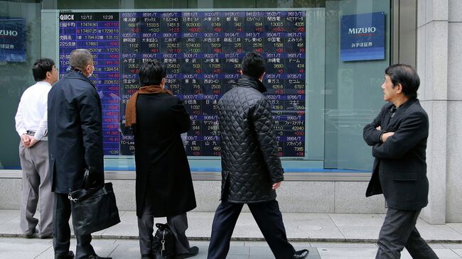 Прохожие в Токио смотрят на экран с биржевыми котировками. Архивное фото