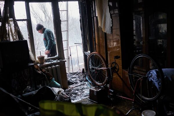 Мужчина в квартире, поврежденной в результате обстрела химического завода и жилого квартала в Донецке