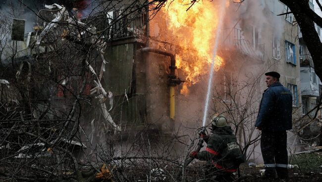 Пожарный тушит пожар в жилом доме, возникший в результате обстрела Донецка украинскими силовиками