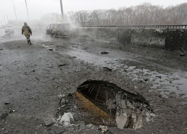 Место попадания снаряда и сгоревший автомобиль в Донецке после обстрела украинскими силовиками