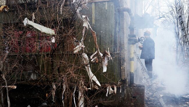 Работник коммунальной службы осматривает жилой дом, поврежденный в результате обстрела химического завода в Донецке