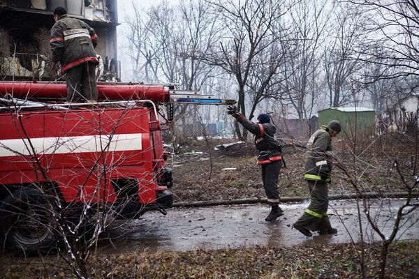 Пожарные у дома, расположенного недалеко от обстрелянного химического завода в Донецке
