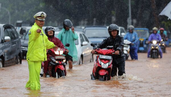 Полицейский регулирует движение транспорта во время наводнения в Джакарте, Индонезия. 9 февраля 2015