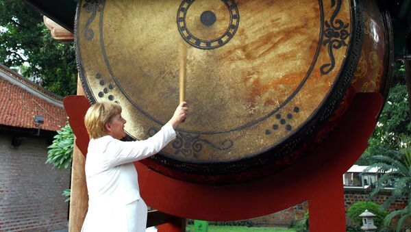 Канцлер Германии Ангела Меркель бьет в гигантский барабан во время визита во Вьетнам. Архивное фото