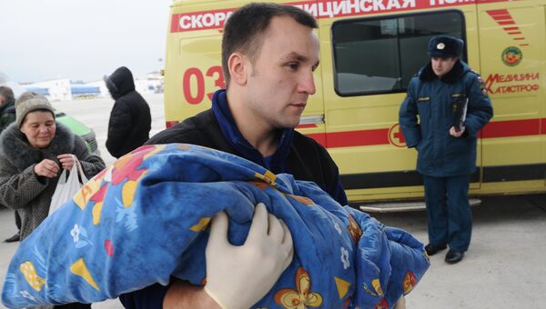 Медицинский сотрудник переносит ребенка, раненого в Донбассе, на борт самолета МЧС РФ в аэропорту Ростова-на-Дону
