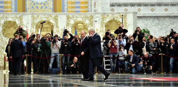 Президент России Владимир Путин и президент Белоруссии Александр Лукашенко проходят мимо журналистов во Дворце независимости в Минске
