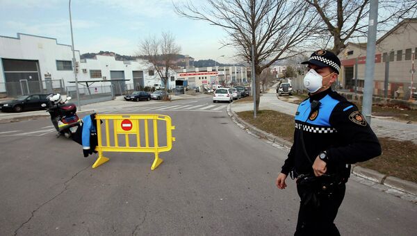 Офицер полиции в защитной маске блокирует улицу, после взрыва азотной кислоты, который произошел в муниципалитете Игуалада, Испания