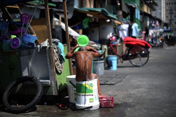 Филиппинец принимает ванну во дворе своего дома в Маниле