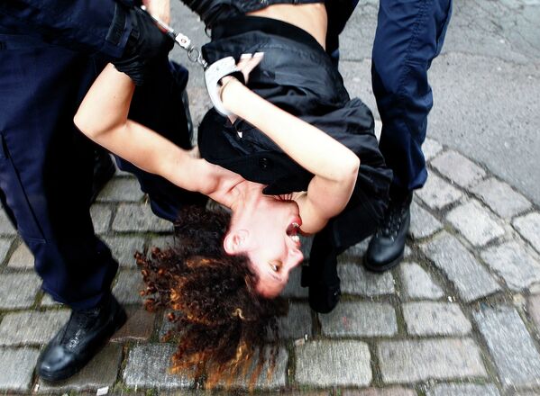 Полиция задерживает активистку Femen во время акции перед зданием суда Лилль. Франция, 10 февраля 2015