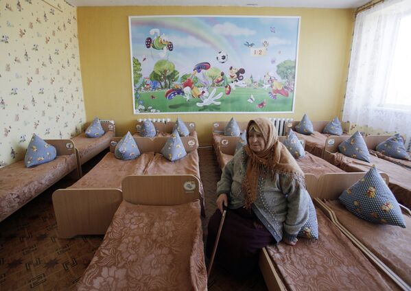 Пожилая женщина сидит на кровати в детском саду