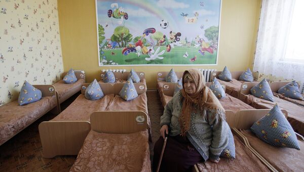 Пожилая женщина сидит на кровати в детском саду. Архивное фото