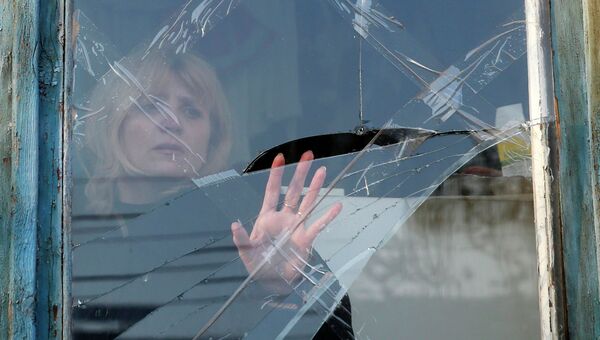 Женщина у разбитого в результате обстрела окна. Донецк, 14 февраля 2015