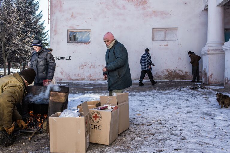 Люди готовят еду на костре перед Домом культуры поселка Мироновский