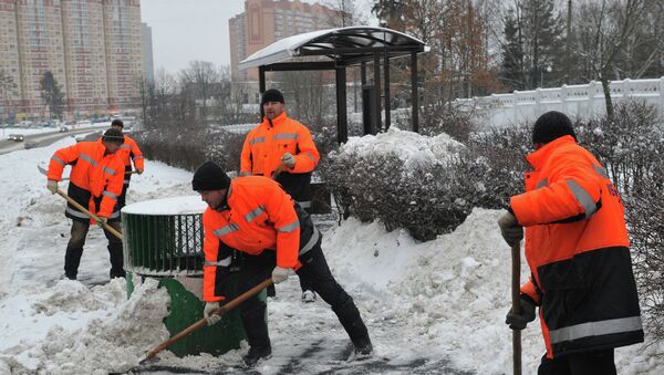 Сотрудники коммунальных служб убирают снег с территории автобусной остановки