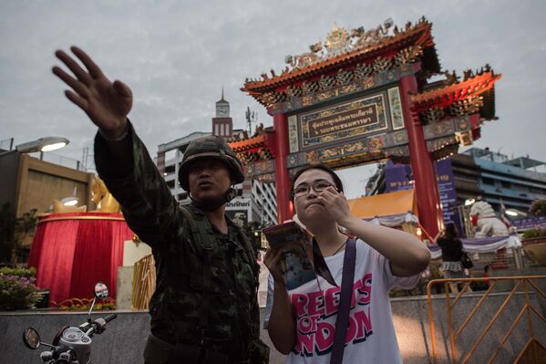 Военный помогает туристке на улицах Китайского квартала в Бангкоке