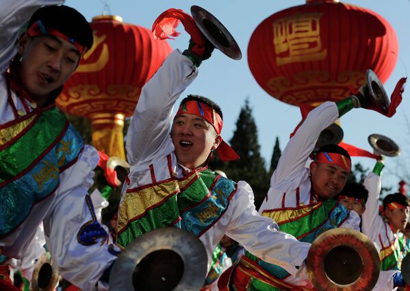 Китайские исполнители одетые в традиционные костюмы танцуют во время открытия ярмарки в канун китайского Нового года в Пекине