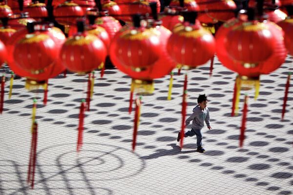 Мальчик бежит в храм под традиционными китайскими фонариками в Куала-Лумпуре