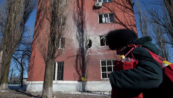 Женщина проходит мимо дома, поврежденного в результате боевых действий в городе Углегорск, Украина