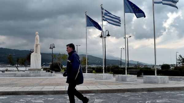 Мужчина проходит мимо флагов ЕС и Греции в порту на острове Самос. Архивное фото.