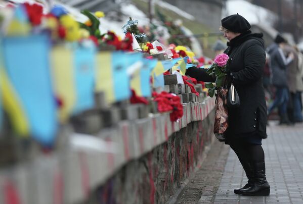 Женщина возлагает цветы в память о погибших во время прошлогодних событий на площади Независимости в Киеве