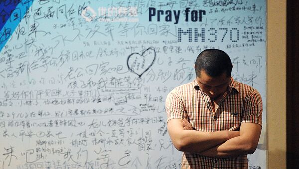 Мужчина стоит на фоне стенда, посвященного пассажирам пропавшего рейса MH370 компании Malaysia Airlines