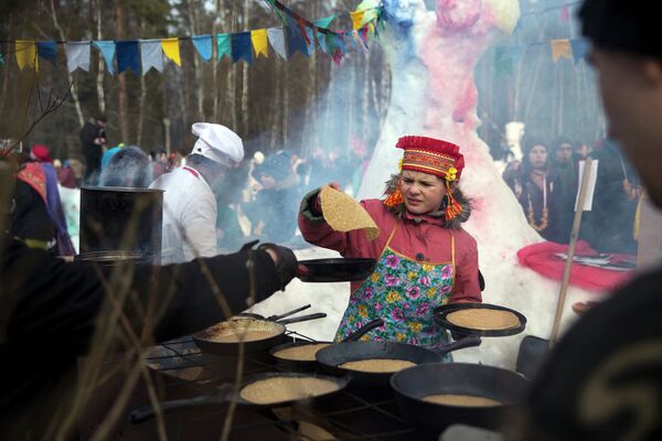 Девочка жарит блины во время празднования масленицы в деревне Хлюпино