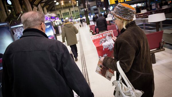 Женщина с вторым после теракта выпуском французского сатирического еженедельника Charlie Hebdo на железнодорожном вокзале в Париже. 25 февраля 2015