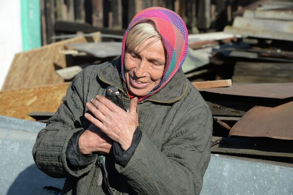 Женщина держит в руках голубя у своего дома в поселке Октябрьский рядом с аэропортом города Донецка