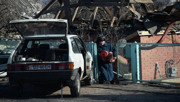 Женщина выносит вещи из своего разрушенного дома в поселке Октябрьский рядом с аэропортом города Донецка. Архивное фото
