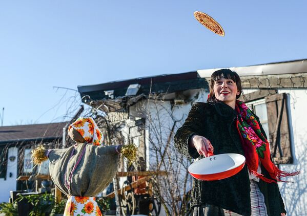 Женщина печет блины во время празднования масленицы в Минске