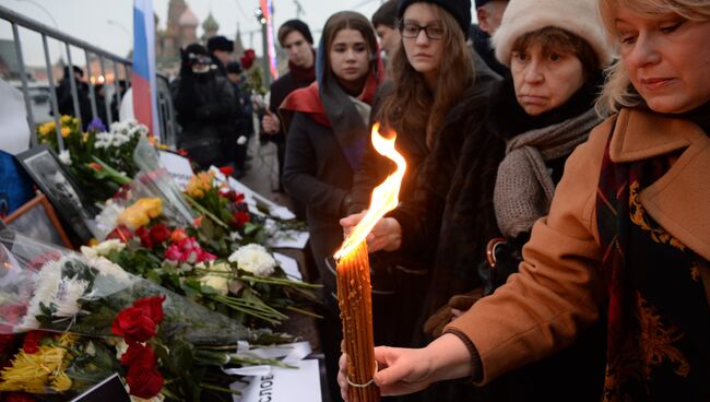 Женщины ставят свечи на месте убийства политика Бориса Немцова