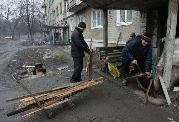 Жители города Дебальцево готовят еду на костре у подъезда жилого многоквартирного дома, пострадавшего в результате боевых действий