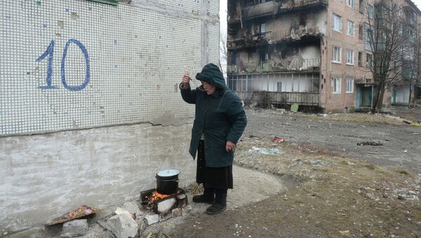 Жительница города Дебальцево готовит еду на костре на улице у жилого многоквартирного дома, пострадавшего в результате обстрелов во время боевых действий. Архивное фото