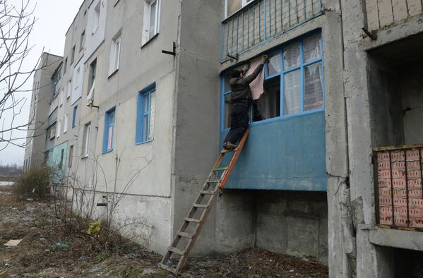 Житель города Дебальцево закрывает листами обоев окна с выбитыми стеклами в жилом многоквартирном доме, пострадавшем в результате обстрелов во время боевых действий