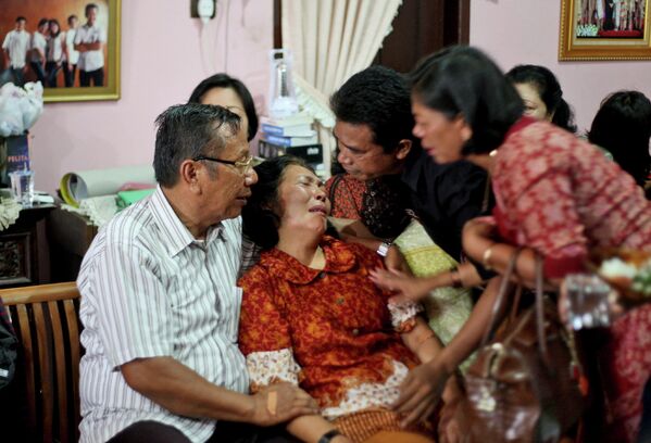Родственники успокаивают родителей одного из пассажиров рейса MH370 Malaysia Airlines