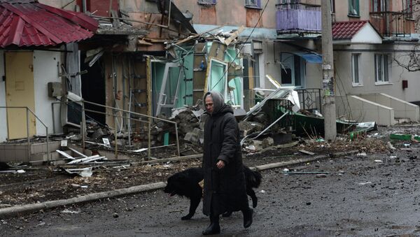Жительница города Дебальцево идет с собакой мимо пострадавшего в результате обстрелов во время боевых действий жилого дома
