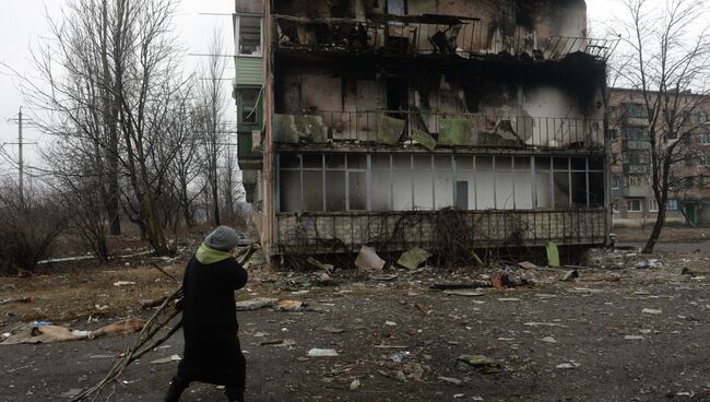 Жительница города Дебальцево несет ветви деревьев для разжигания костра, на котором жильцы пострадавших жилых домов, готовят еду. Архивное фото