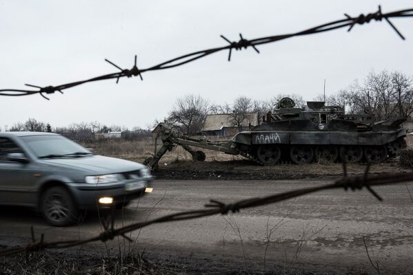Автомобиль проезжает мимо брошенного танка украинской армии в Очеретино