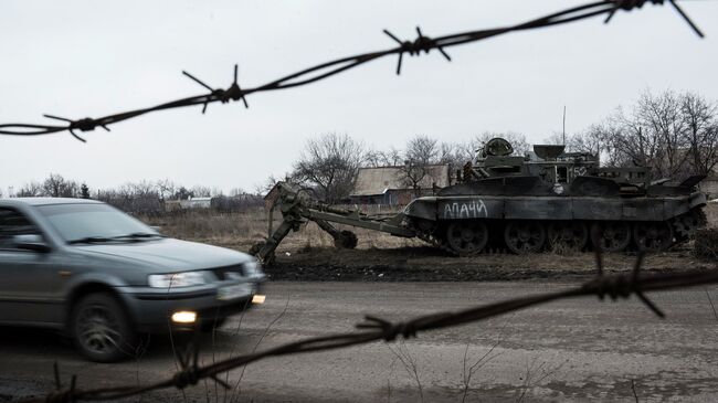 Автомобиль проезжает мимо брошенного танка украинской армии в Очеретино